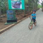 Manfaatkan Jalan Hasil TMMD, Seorang Anak Bermain Sepeda