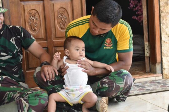 Personil Satgas TMMD 106 Bercengkrama bersama anak Warga