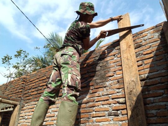 Diatas Tangga, Prada Ahmad Irfan Potong Papan Kayu di Rehab RTLH