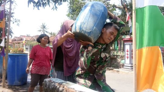 Walau berat, Kopda Tofik Tetap Mengangkat Galon Air Bersih Ke Rumah Mbah Minarti