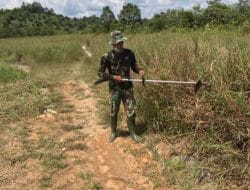 Anggota Satgas TMMD Membersihkan Area Kantor Desa