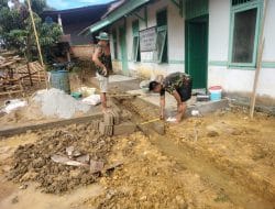 Anggota satgas TMMD ukur lebar dari parit yang di buat untuk sekeliling puskesmas pembantu