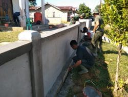 Anggota satgas TMMD bersama warga melanjutkan plasteran dinding pagar gereja