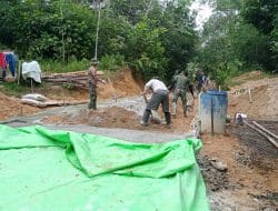 Anggota satgas TMMD bersama warga melanjutkan plasteran dinding pagar gereja