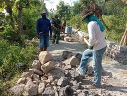Anggota Satgas TMMD Menghamparkan Batu Buat Penahan Jalan