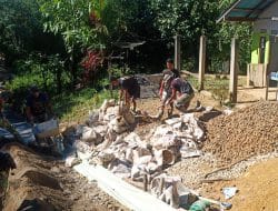 Anggota satgas TMMD kompak dalam angkut material batu kerikil