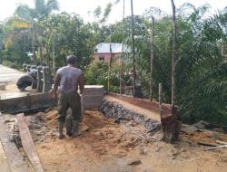 Anggota satgas TMMD menimbun pinggiran jembatan menggunakan pasir
