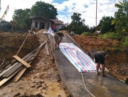 Anggota Satgas TMMD Membuka Plastik Cor Jalan Rabat Beton