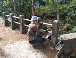 Anggota satgas TMMD membersihkan sisa sisa semen pada pembangunan jembatan