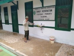 Anggota Satgas Membersihkan Sisa-sisa Material Pembangunan Pustu