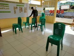 Anggota satgas TMMD rapikan kursi di aula desa