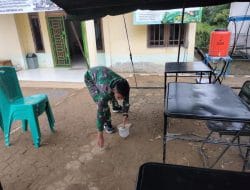 Anggota Satgas Membersihkan Halaman Kantor Desa Sentangau Jaya