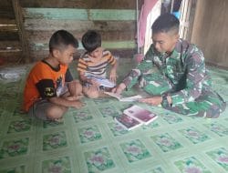 Anggota satgas TMMD mengajari anak anak untuk membaca dan menulis