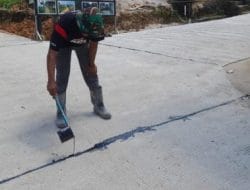 Guna Lebih Tahan Lama, Satgas TMMD Ke 120 Kodim 0316/Batam Menyiramkan Aspal Panas Ke Semenisasi Jalan